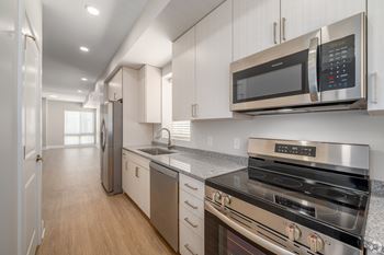 A modern kitchen with stainless steel appliances and wooden floors. at Park Lamont Townhomes Apartments, Ohio